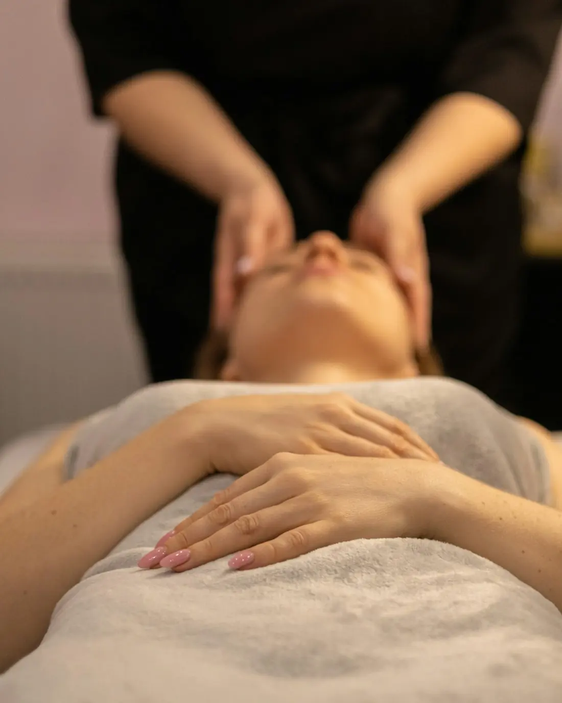 A specialist carrying out a facial treatment in soft, warm light