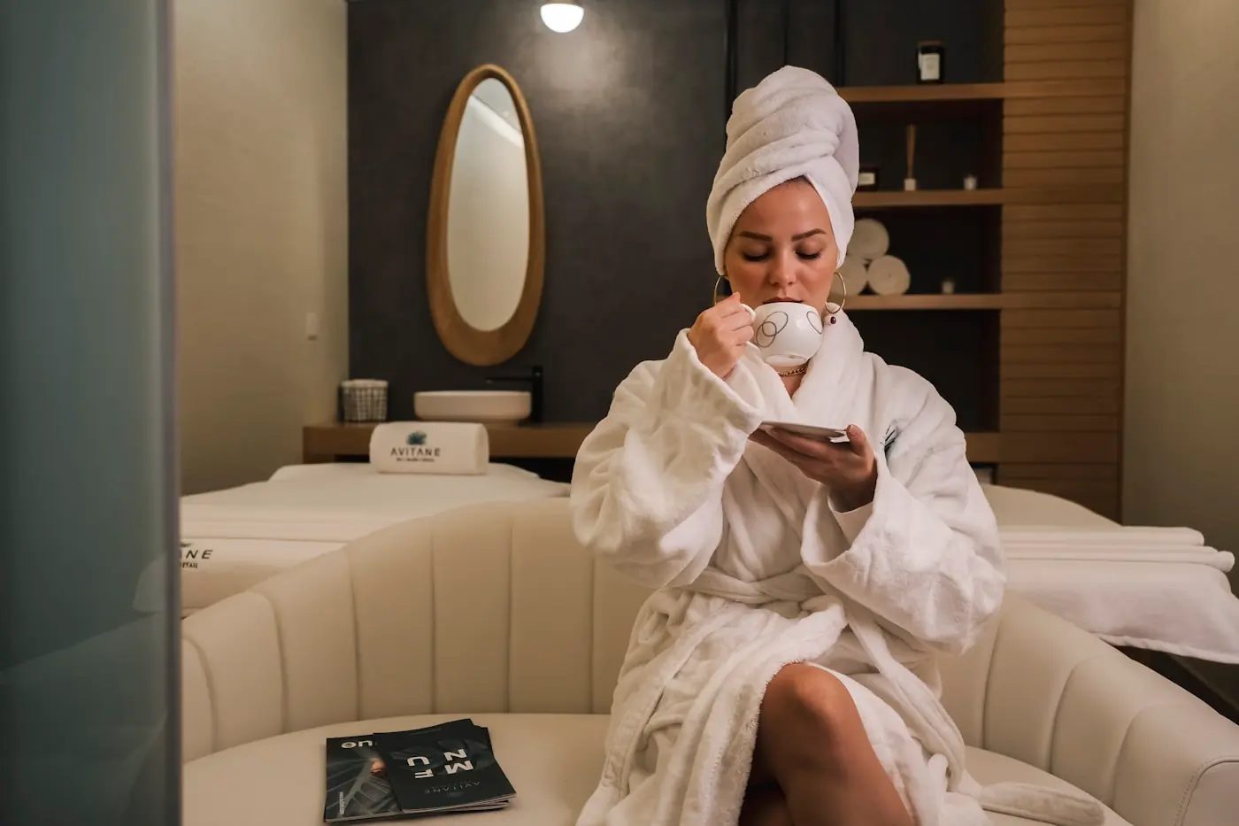 Client relaxing with a warm drink in a softly lit clinic lounge before her consultation